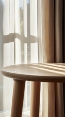 Sunlight streams through sheer curtains onto a light wood side table.