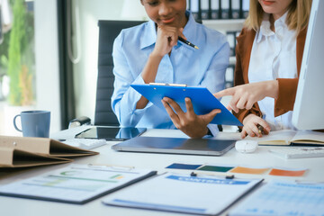 An African American businesswoman and a Caucasian woman work at analyzing market data, developing business strategies,discussing financial growth while using a laptop spreading money for investment