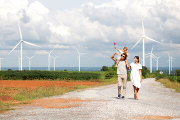 Happiness family walking wind turbine farm while father piggyback of daughter together, environment...