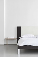 Modern minimalist bedroom design featuring a bed with soft linens and a side table