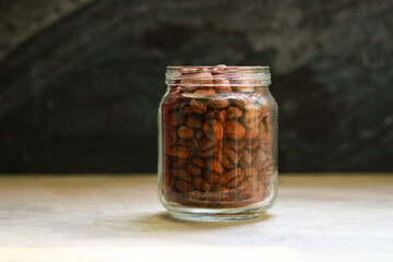 Coffee beans in a glass jar on a wooden table.
