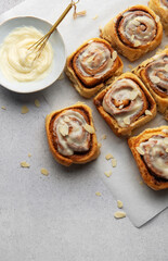 Freshly baked cinnamon rolls topped with cream cheese frosting and almond slivers