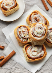 Delicious cinnamon rolls topped with icing and almonds on baking paper