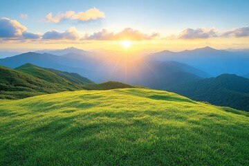 Fototapeta premium Stunning sunrise over mountains with vibrant green grass, lush scenery, and warm sunlight casting a glow on the landscape.
