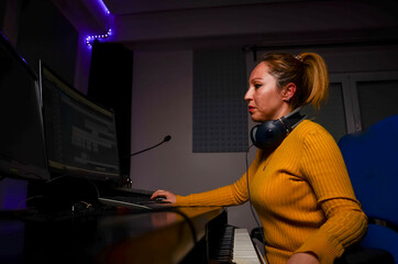 Music producer working in recording studio using computer and keyboard