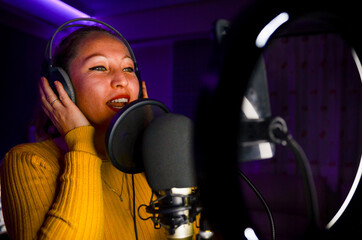 Singer wearing headphones recording song in recording studio