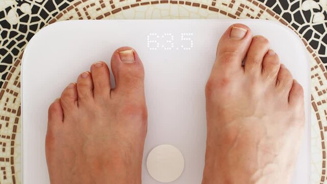 without a face. A person with bare feet is weighed on electronic scales. weight control on a diet. congenital anomalies of the feet.