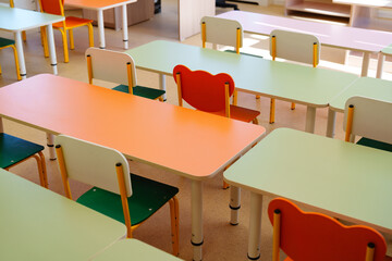 Brightly colored classroom furniture arranged in a learning space with empty desks and chairs...