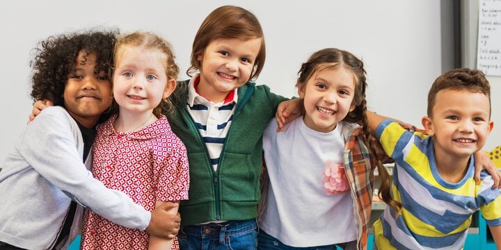 Diverse group of happy children smiling, hugging, and posing together in a classroom. Kids, friendship, and joy are captured in classroom. Happy kids embrace in front of whiteboard in classroom.
