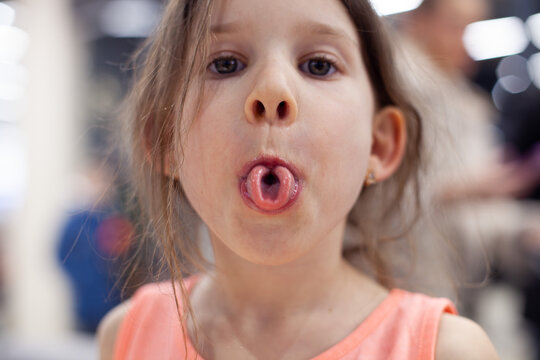 Girl rolling tongue into tube, close up. Articulation logopedic for mouth, speech therapy, tongue gymnastics concept.