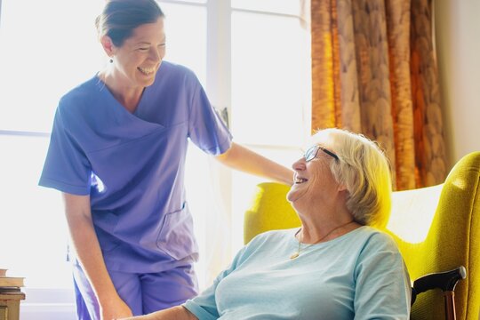 Caregiver in scrubs take care elderly woman at healthcare center. Medical healthcare caregiver assist elderly woman share warm happy moment. Happy elderly woman and healthcare staff assistant