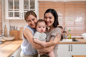 Portrait of Asian lesbian couple caring for and raising baby boy at home. 