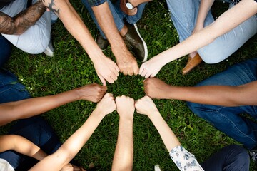 Diverse community with hands in a circle. Nature and environment. Diverse group of people hands together in unity. Group of diverse hands fist in circle on grass. Diverse people hands fists together