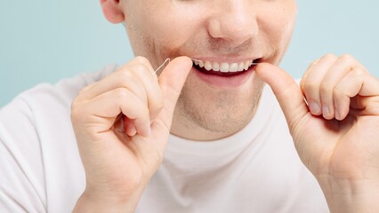 Close-up of a person flossing teeth. Flossing helps maintain dental hygiene. The person uses dental floss to clean teeth, ensuring healthy gums and teeth. Man using dental floss, clean teeth, hygiene.