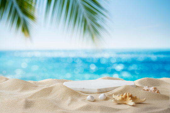 Tropical sand beach with marble podium for summer product display on blurred sea horizon background
