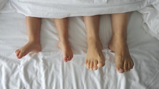 Child and mother wiggle toes sticking out from under blanket