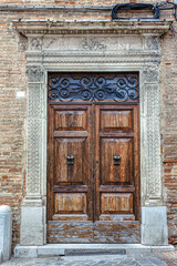 Door Catholic Cathedral in the city of Urbino. Beautiful entrance of the Catholic Cathedral showcasing intricate stonework and wooden door. Urbino, Marche, Italy