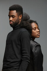 Obraz premium Portrait of a young Black couple dressed in stylish black attire, showcasing deep emotions against a neutral backdrop, perfect for conveying intimacy and connection