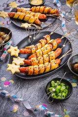 Carnical food, long sausages wrapped in yeast dough, corn dog with mustard and olives