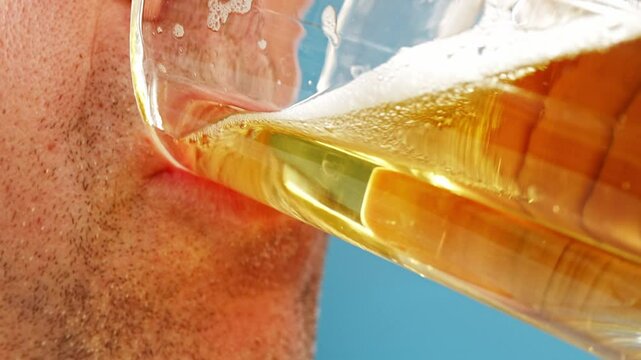 Close-up. A man with stubble drinks beer. A cold refreshing drink.