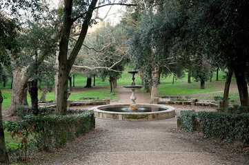 Elegant stone fountain in a lush, tree-filled park setting