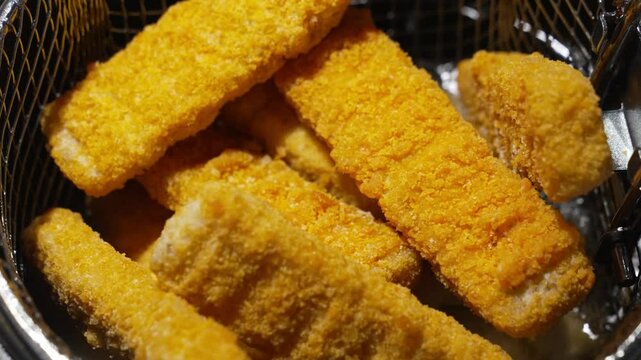 fish sticks cooking into heated vegetable oil in a deep fryer. cooking in hot oil.