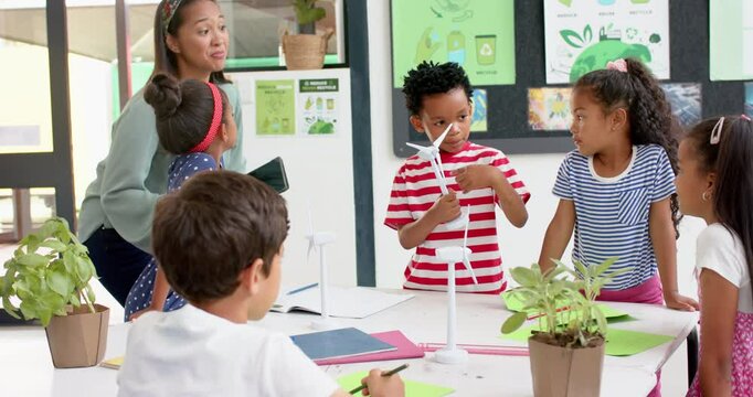 In school, teacher and students discussing science project with wind turbines
