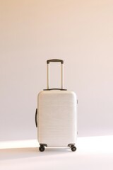 Sleek suitcase stands against soft pastel backdrop, emphasizing