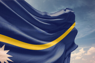 Waving flag of Nauru in blue sky. Nauru flag on pole for Independence Day. The symbol of the state on wavy fabric.