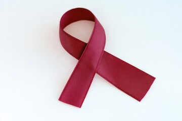 A single red ribbon lies flat on a white surface