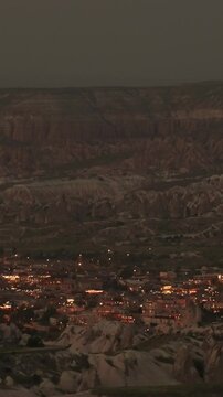 Vertical parorama video. City lights illuminating Goreme town in the Cappadocia desert at night. Magical atmosphere the dark sky and highlighting the stunning rock formations. Turkey tour travel 