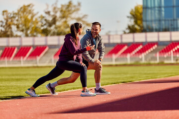 Obraz premium Two People Stretching and Enjoying Outdoor Exercise on a Sunny Running Track