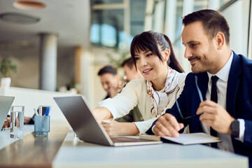 Colleagues Collaborating on a Project Using a Laptop in a Modern Workspace