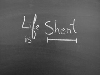 Fototapeta premium Life is short handwritten on a chalkboard in white