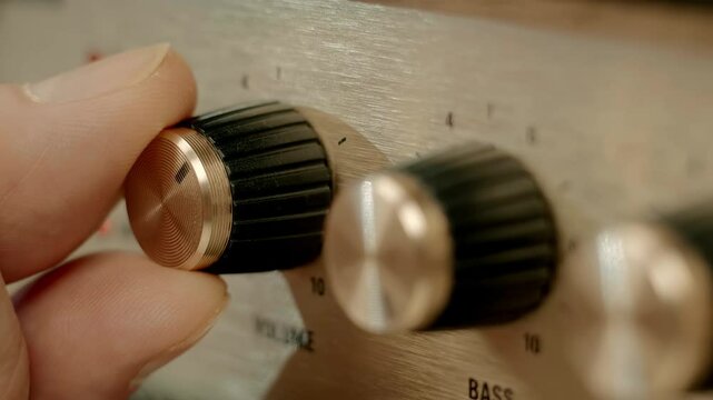 A man's finger presses the on off switch on a modern retro-style amplifier (portable loudspeaker) and adjusting the volume. Closeup. Macro. Shallow depth of field. Shot in motion