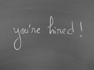 You're hired written on a chalkboard surface in white lettering