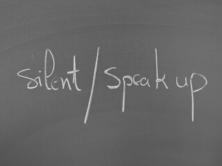 Silent or speak up written on a chalkboard in white chalk