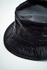A black leather hat sits alone on a white surface, perfect for styling or photography props