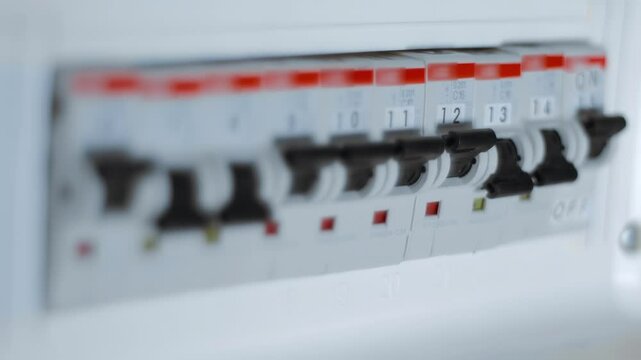Home white electrical distribution board with rows of switches numbered to indicate which line each one serves. Closeup. Macro. Shallow depth of field. Follow focus