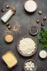 Calcium source - dairy products, sesame and poppy seeds, parsley, dark grunge background, top view, flat lay, vertical. Food rich in calcium, copy space