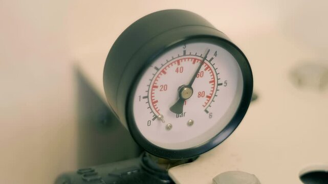 A pressure gauge with an oscillating pointer indicating unstable pressure in a water (fuel, gas, oil, petroleum or chemical solution) pipeline. Closeup. Macro. Shot in motion. Shallow depth of field