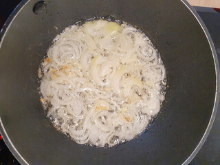 Chopped onions are fried in a frying pan until golden brown. Cooking process. Onions are fried in a frying pan