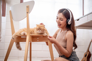 Asian young woman play with little cat with happiness in bedroom at home.