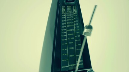 New, modern, shiny, black metronome, with a swinging pendulum, accurately beats in time, helping the musician not to lose the rhythm, on a light background. Closeup. Macro. Shot in motion