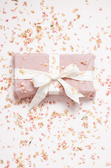 Sustainable wrapped present and dried petals confetti. Zero waste holiday background.