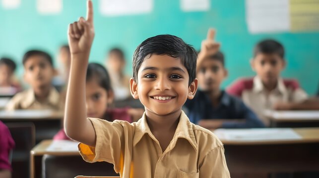 Indian schoolboy raising hand in classroom, eager to answer question