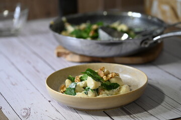Close-up view of homemade potato gnocchi being prepared in the kitchen, with a creamy cheese sauce...