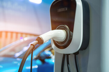 Electric car charger plug recharging the grey vehicle at a charging station. electric car charger green energy environment friendly driving vehicle station. Modern transport fuel of future.