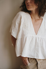 Woman with curly hair wearing loose white blouse and beige pants. Casual carefree pose. Relaxed and...