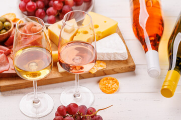 A delectable arrangement of various cheeses, fresh grapes, prosciutto and wine